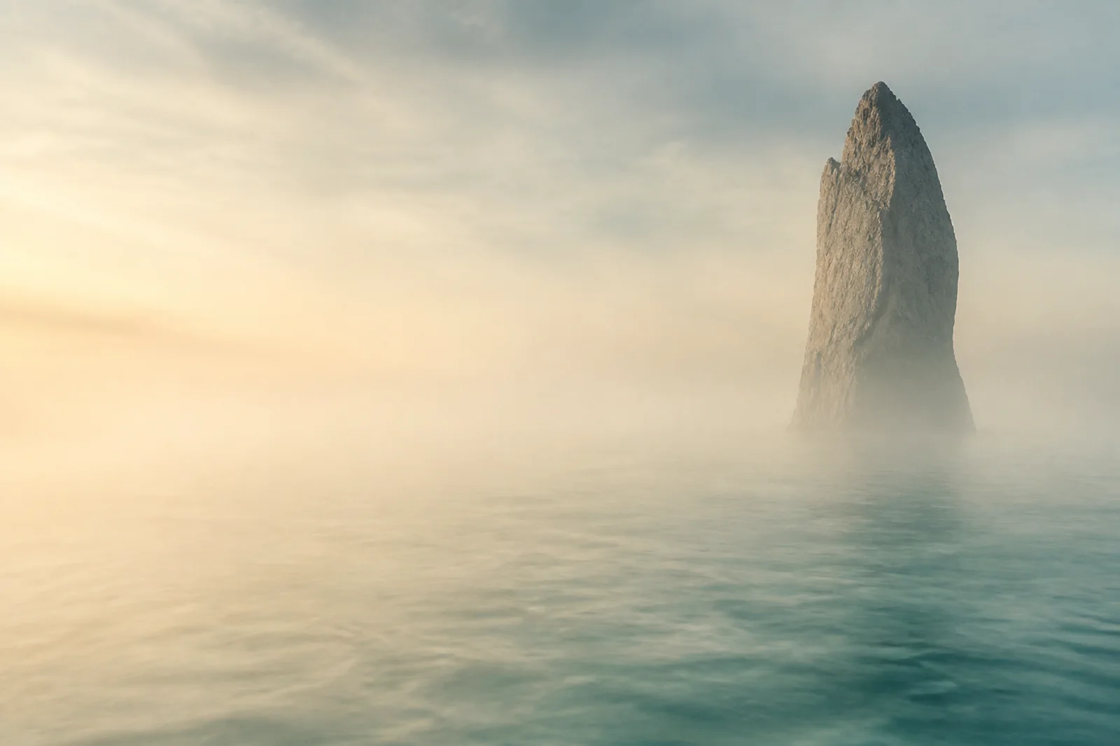 Premium coastal landscape background with an isolated sea monolith, dawn fog, and open text-safe space
