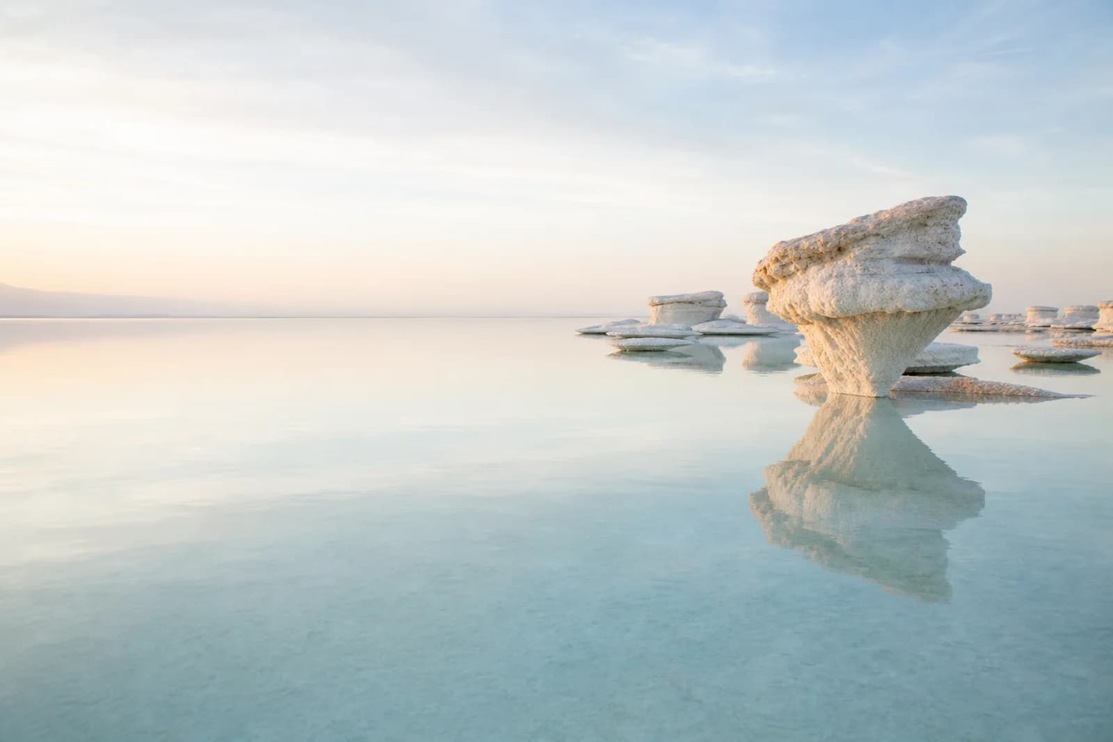 Premium editorial landscape background with mirror water, sculptural salt formations, and open pale copy space
