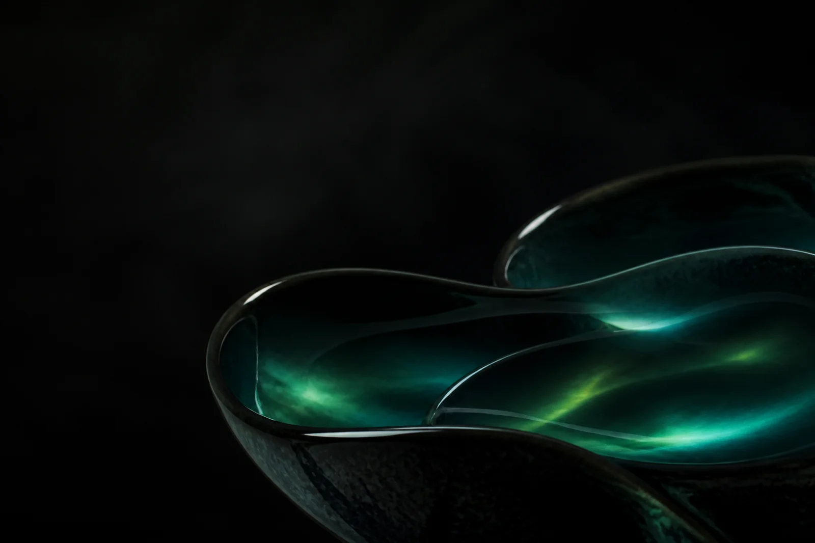 Dark onyx ceramic abstract background with deep teal aurora reflection and open upper-left space