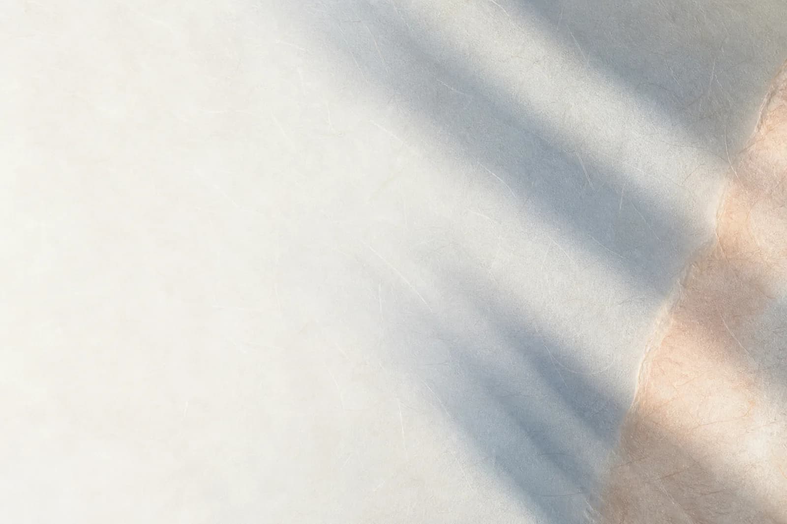 Premium light paper background with silver-blue shadow bands, delicate fiber texture, and a warm peach edge